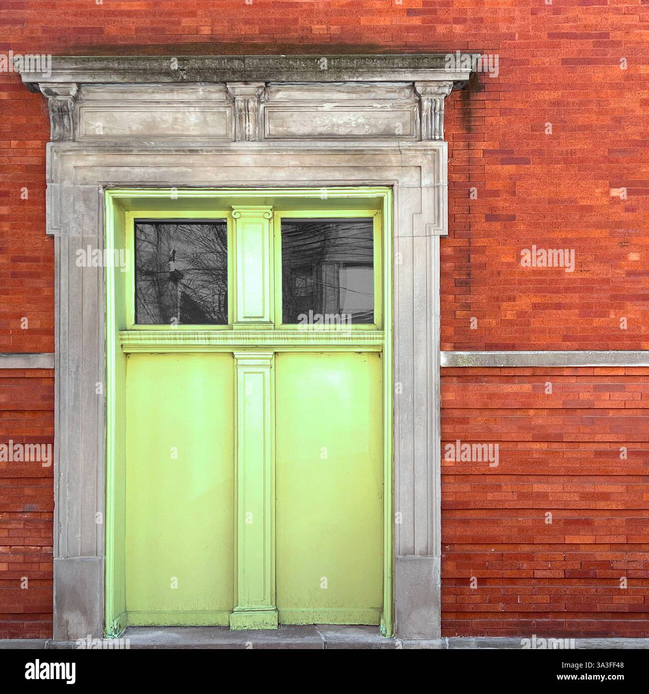 Porta verde lime posta all'interno di uno storico edificio in mattoni rossi, incorniciato da una facciata in pietra ornata. - Immagine stock catturata con smartphone