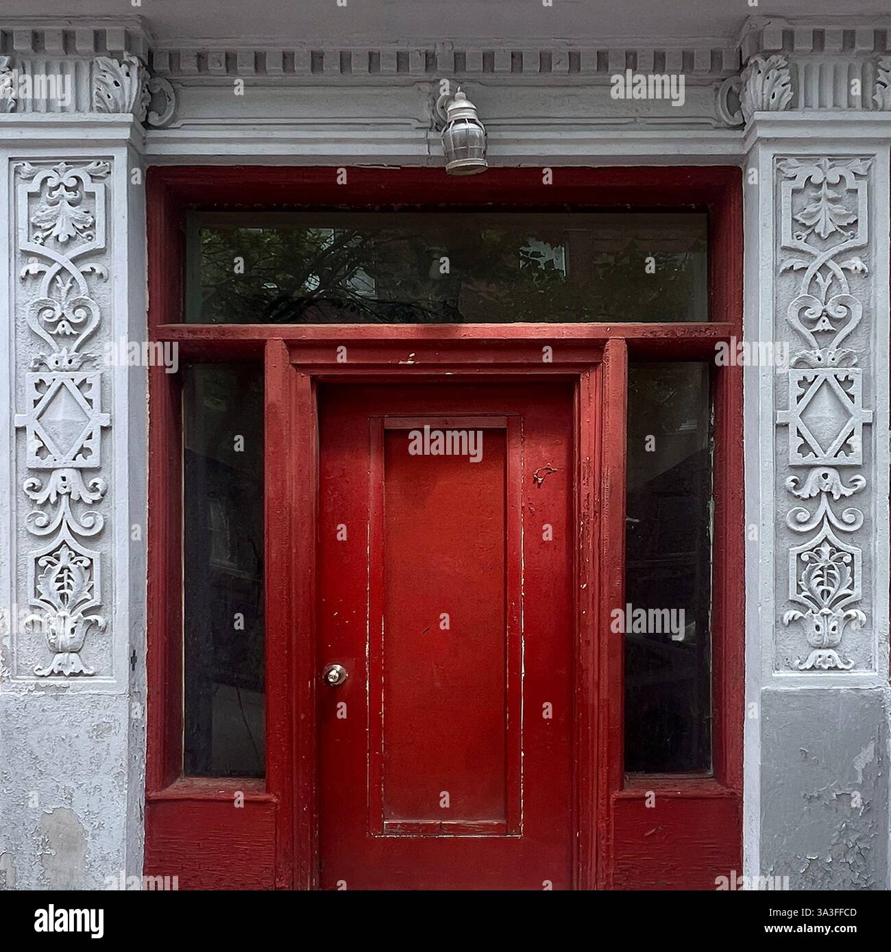 Una porta rossa ornata incorniciata da intricati dettagli architettonici bianchi che mostrano il fascino vintage di Chicago Foto Stock