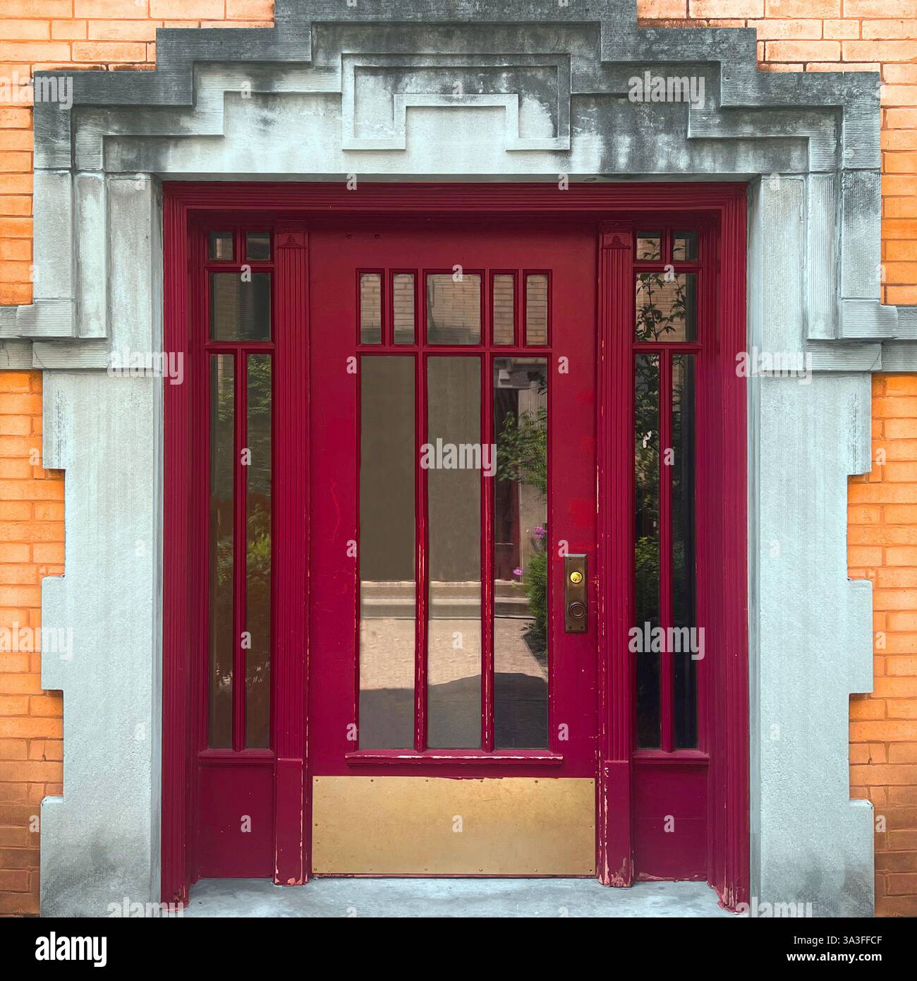 Ingresso Art Deco rosso incorniciato da dettagli geometrici in pietra calcarea che mostrano il fascino architettonico classico di Chicago. - Immagine stock catturata con smartphone