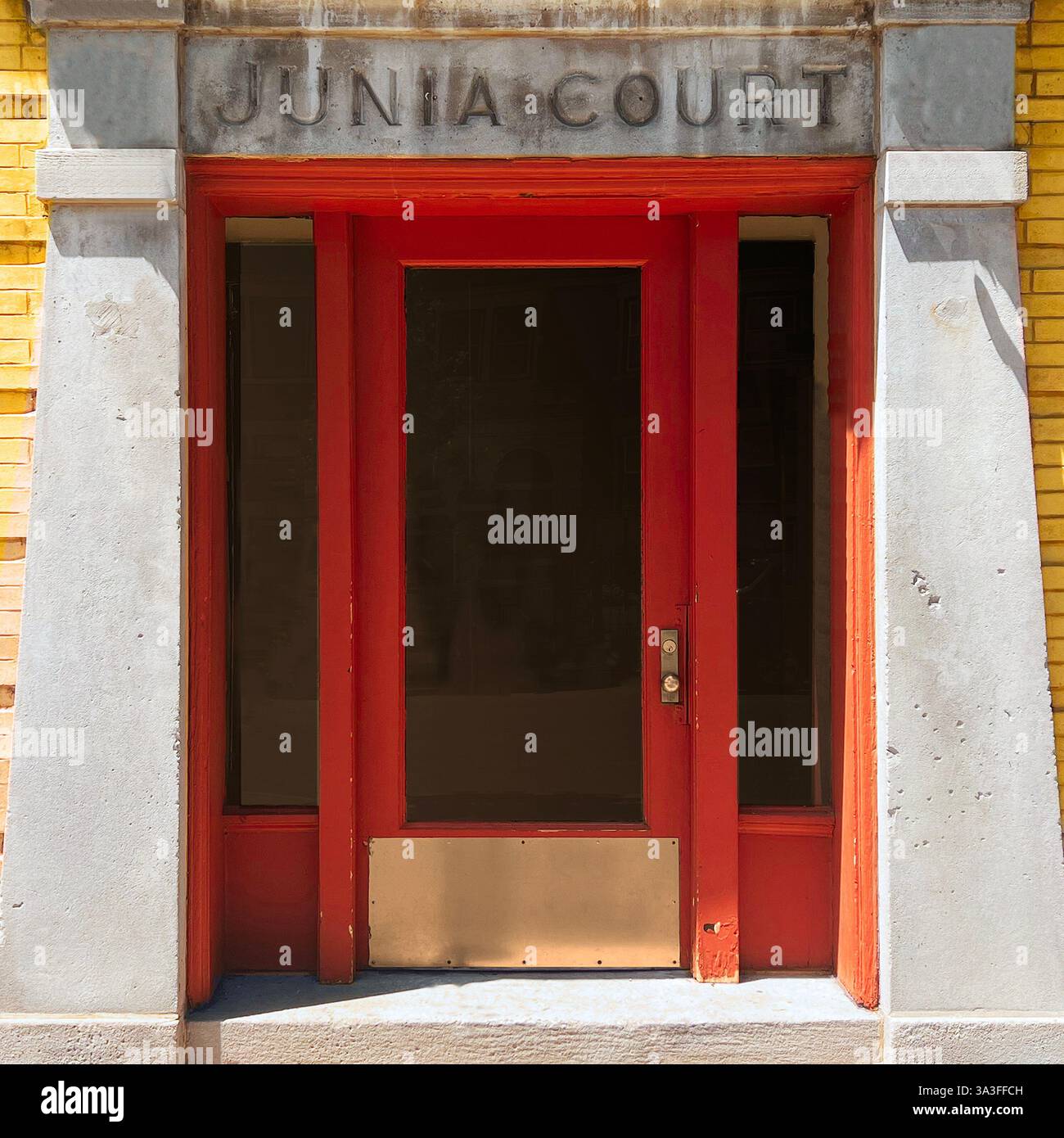 Una storica entrata rossa, incorniciata da audaci colonne di cemento e mattoni gialli, che riflettono la classica architettura di Chicago. - Immagine stock catturata con smartphone