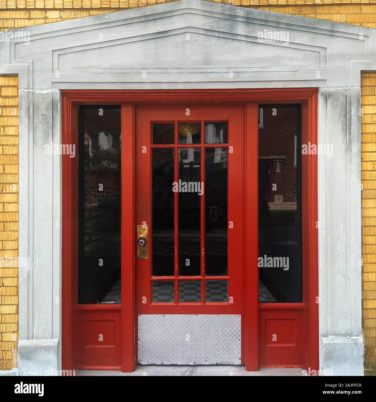 Porta d'ingresso rossa incorniciata da un classico frontone in pietra e adagiata all'interno di una facciata in mattoni gialli a Chicago - Immagine stock catturata con smartphone