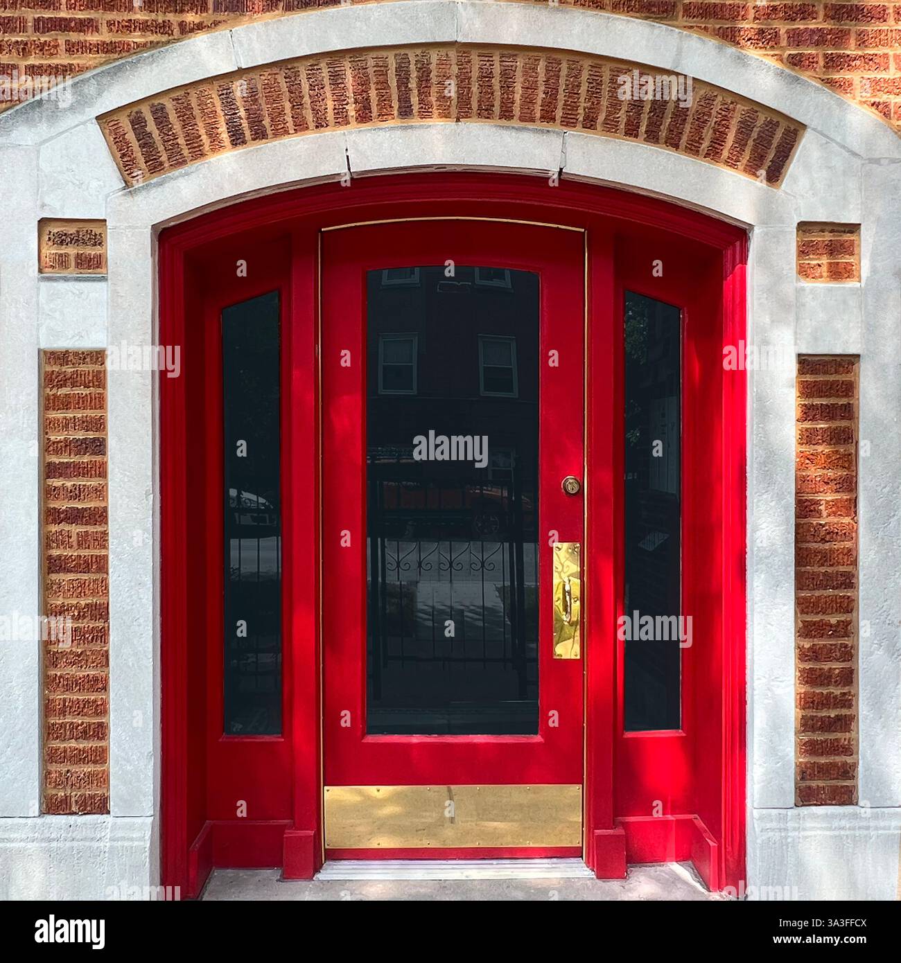 Porta ad arco rossa, incorniciata da una facciata in mattoni e pietra calcarea, che riflette il fascino dell'architettura classica di Chicago. - Immagine stock catturata con smartphone