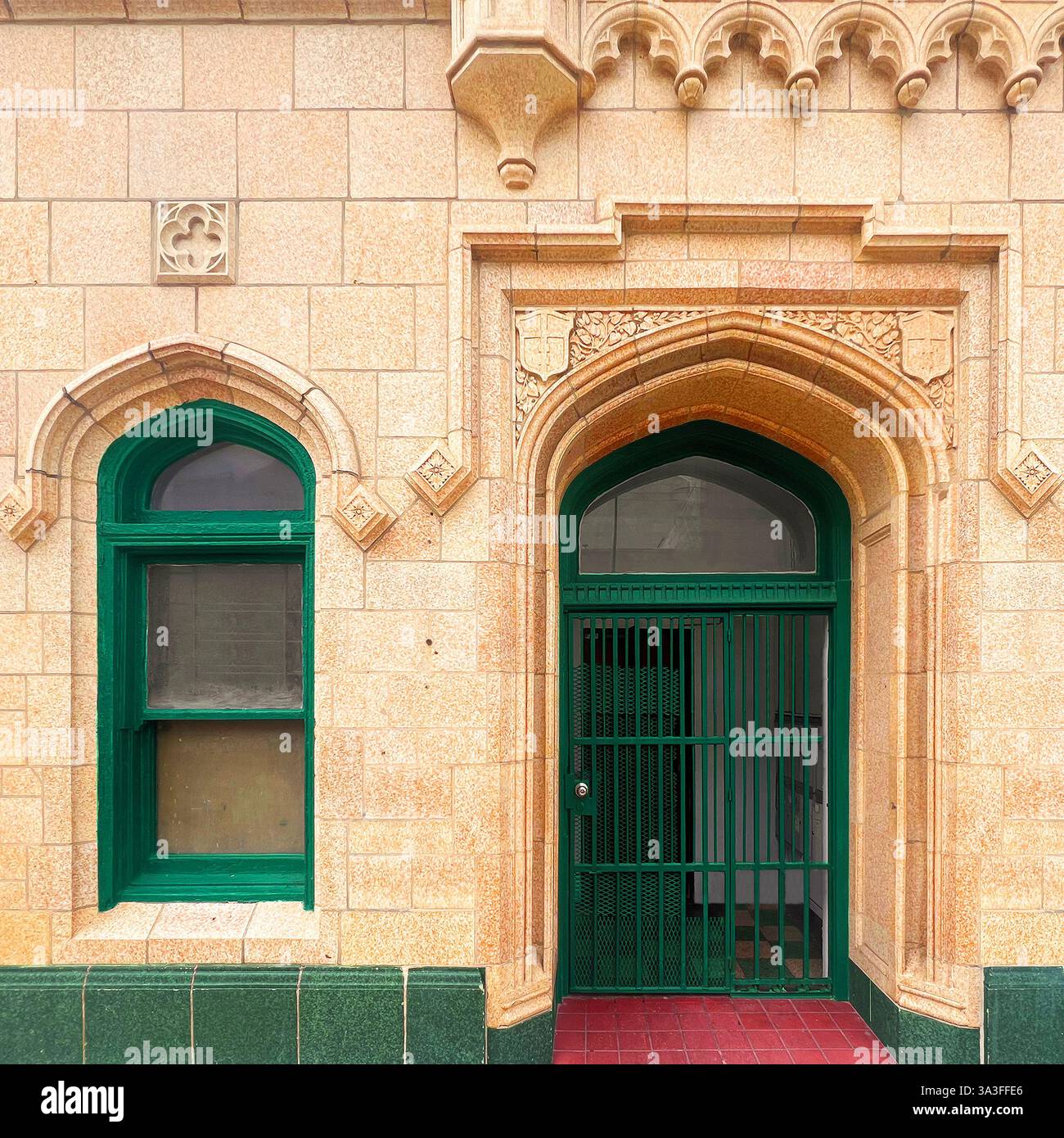 Un'elegante porta verde ad arco con una finestra coordinata, posta all'interno di una facciata gialla a Chicago. - Immagine stock catturata con smartphone
