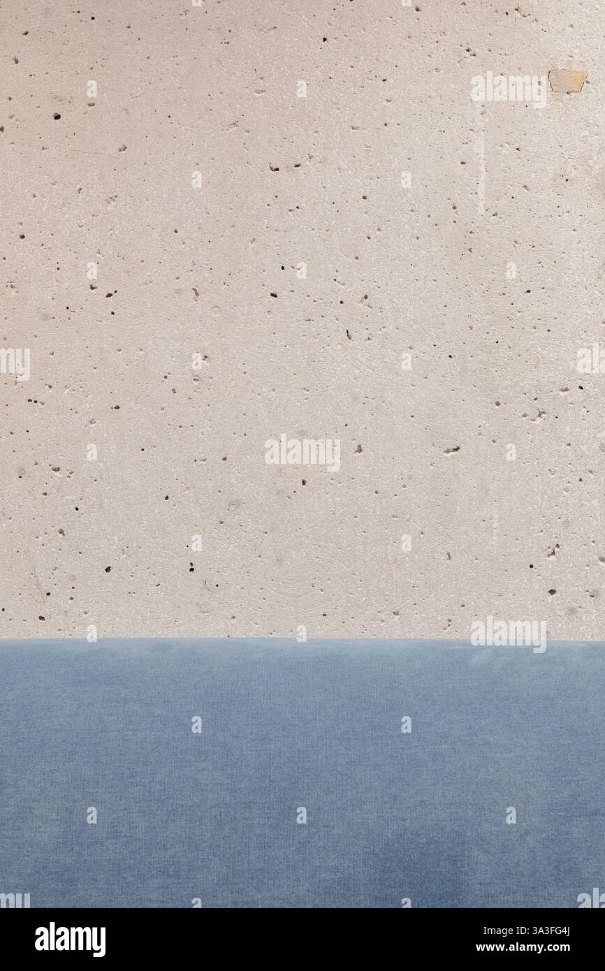 Composizione minimalista caratterizzata da una parete in cemento testurizzato accostata a una serena distesa di tessuto blu crea armonia visiva Foto Stock