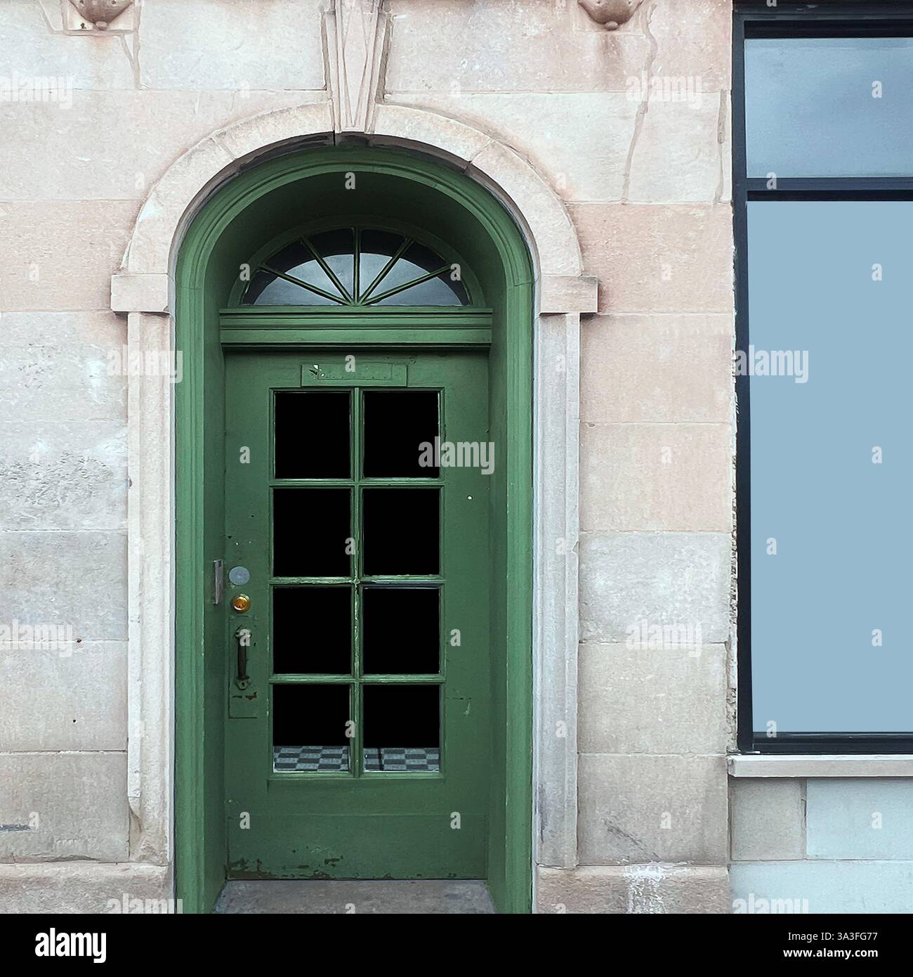 Classica porta verde ad arco con vetri decorativi adagiati su una facciata in pietra a Chicago. - Immagine stock catturata con smartphone