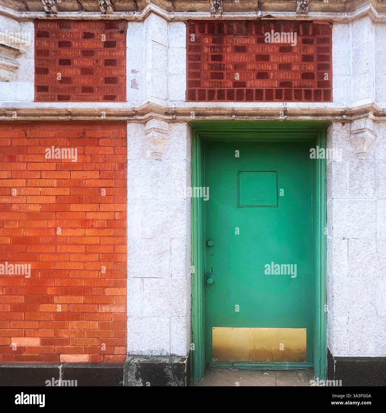 Porta in metallo verde brillante con piastra in ottone in una facciata ornata in arancione e mattoni con decorazioni in pietra a Chicago. - Immagine stock catturata con smartphone