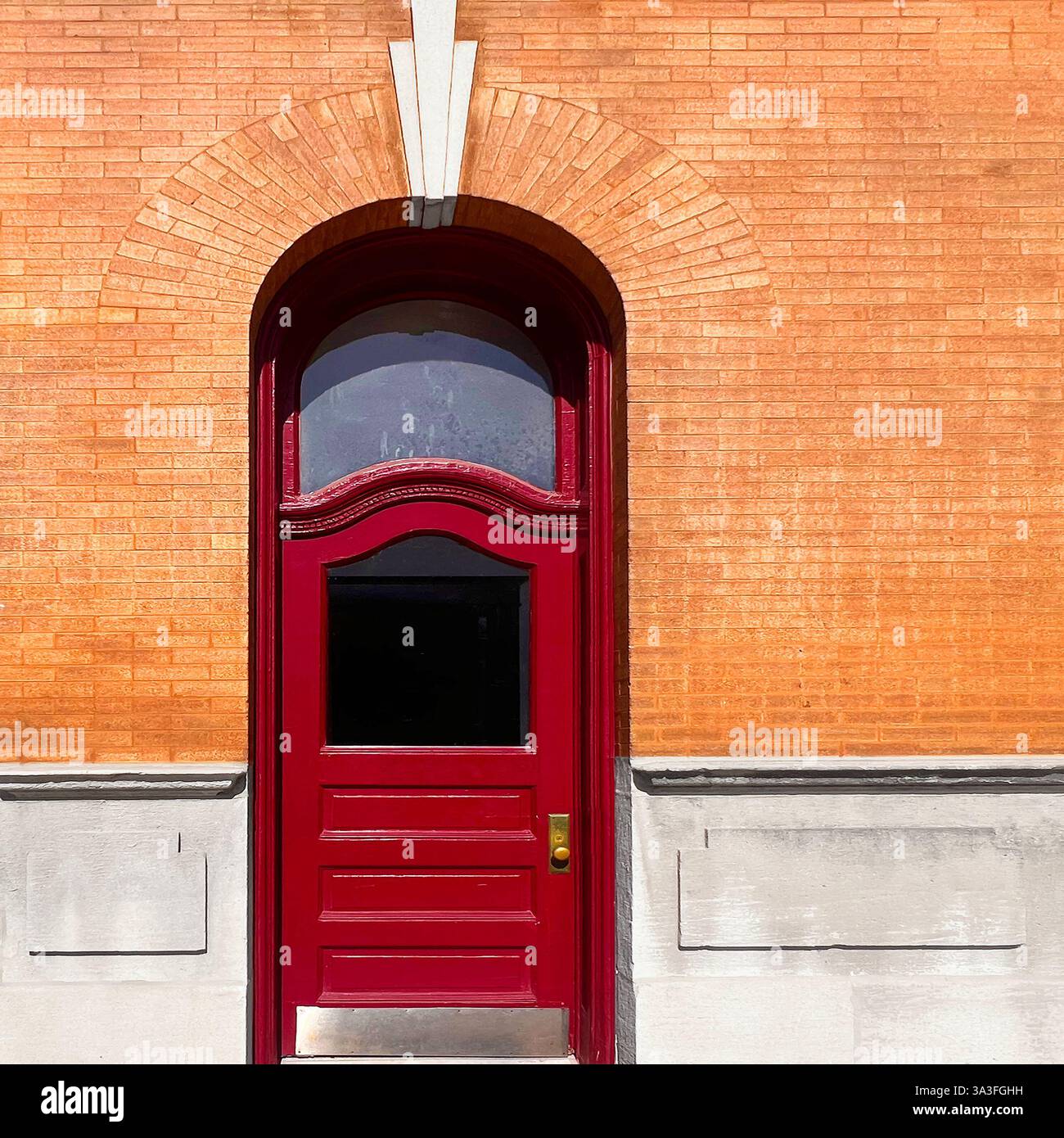 Porta rossa vintage con finestra a poppa ad arco incastonata in una parete di mattoni arancioni con dettagli decorativi in pietra a Chicago. Foto Stock