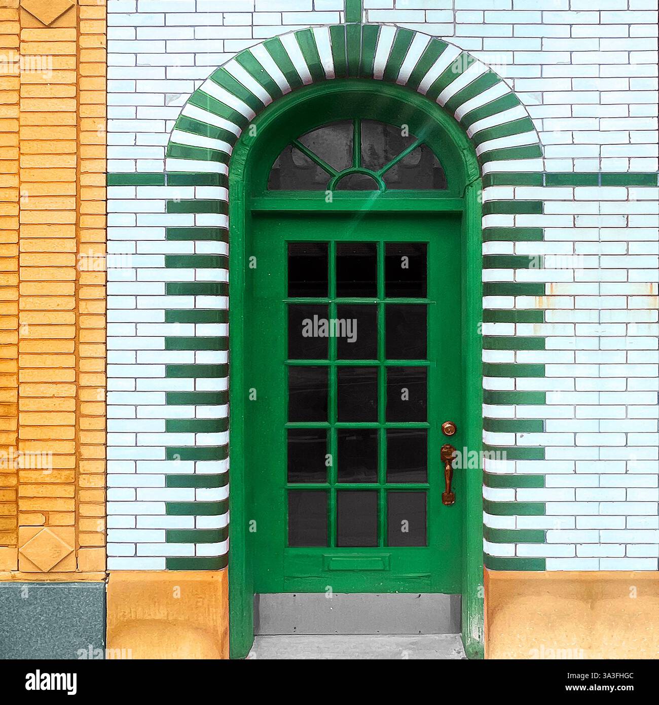 Porta verde con pannelli di vetro incastonata in un suggestivo arco di piastrelle bianche e verdi, mattoni smaltati bianchi a Chicago. Foto Stock
