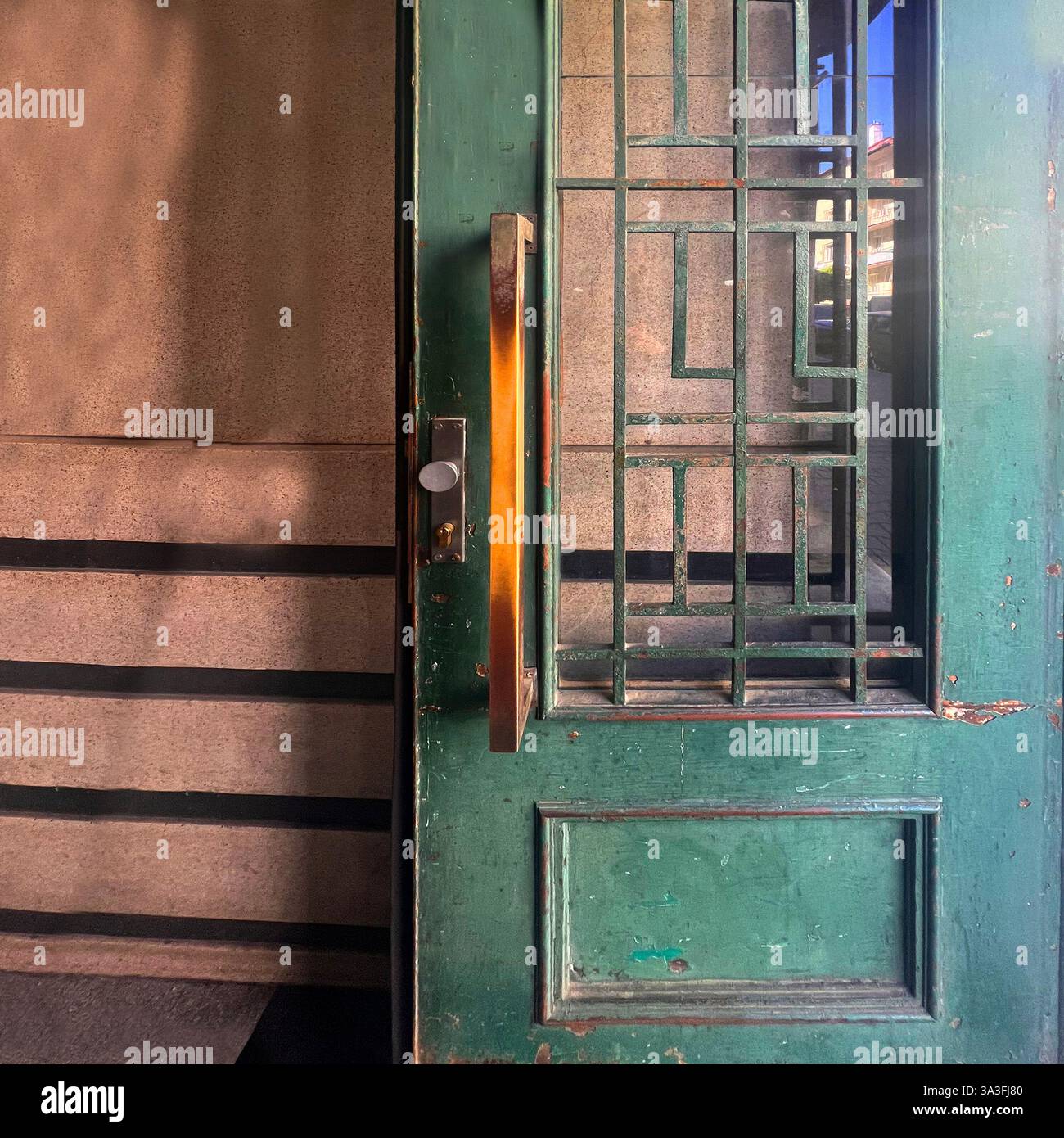 Una porta in legno verde vintage con ferro geometrico e patina usurata si erge parzialmente aperta in uno storico edificio di Cracovia Foto Stock
