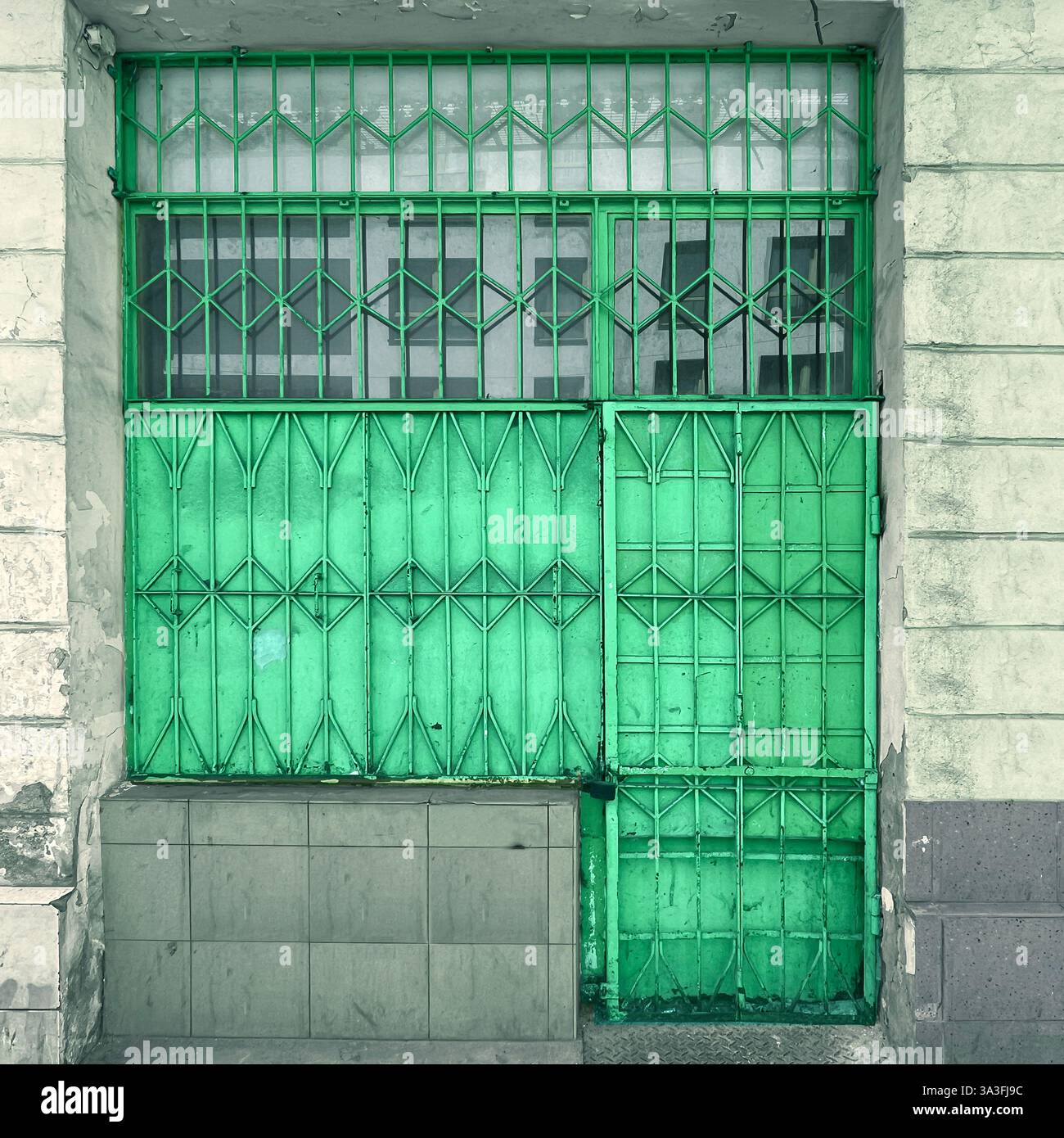 Un cancello in metallo verde con passerella con intricati motivi geometrici che assicurano l'ingresso di un edificio a Varsavia, Polonia - Immagine stock catturata con smartphone