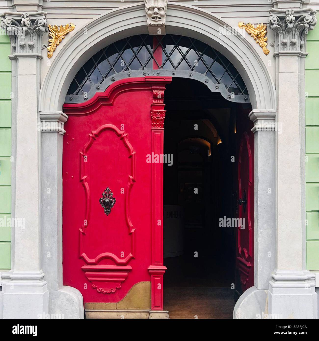 Splendida porta ad arco rossa con dettagli ornati e dettagli scultorei a Wrocław, Polonia - Immagine stock catturata con smartphone