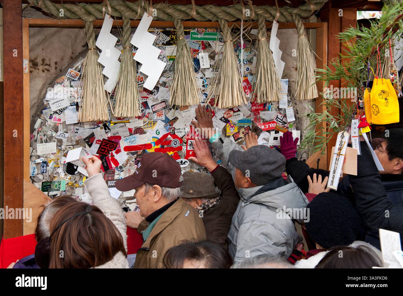 I fedeli toccano il pannello di preghiera in legno coperto di biglietti da visita che desiderano prosperità e buona fortuna al santuario Imamiya Ebisu Jinja di Osaka, Giappone Foto Stock
