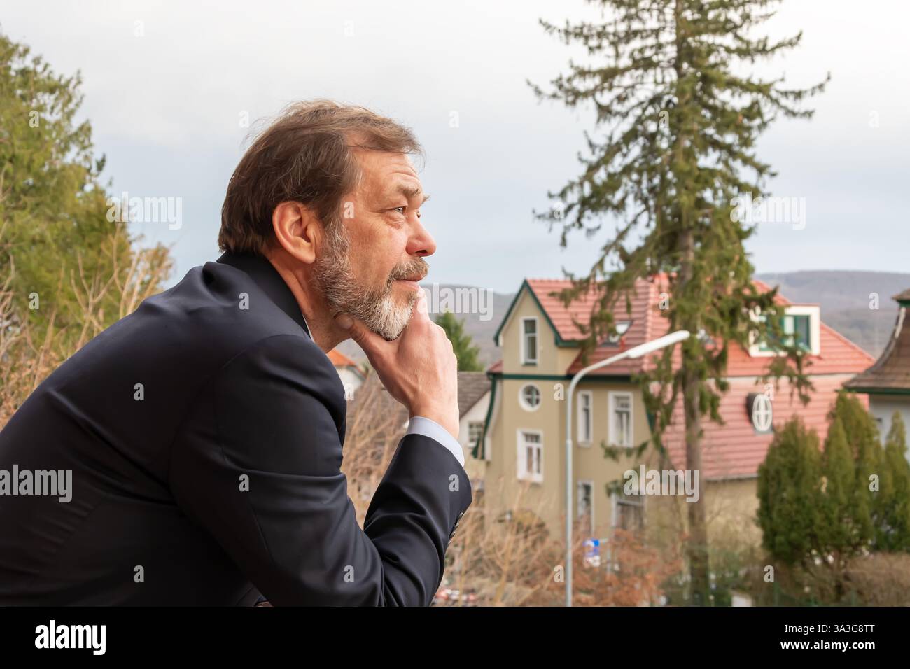 Un uomo anziano sicuro di sé di 50-55 anni in un costume da lavoro gode di una vista sulla campagna Foto Stock