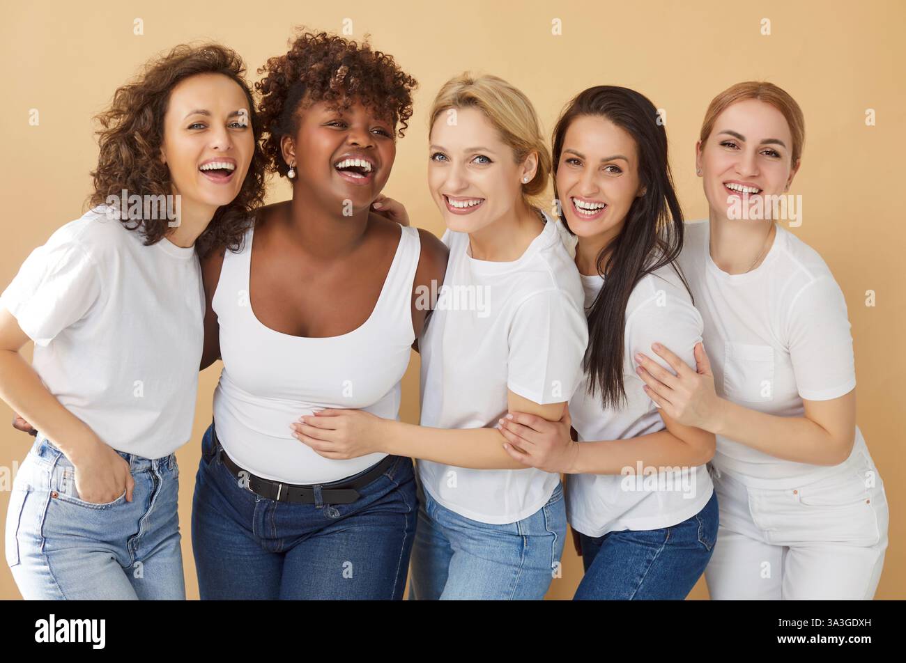 Felice gruppo di giovani donne diverse che guardano allegramente alla telecamera isolata sullo sfondo dello studio. Foto Stock