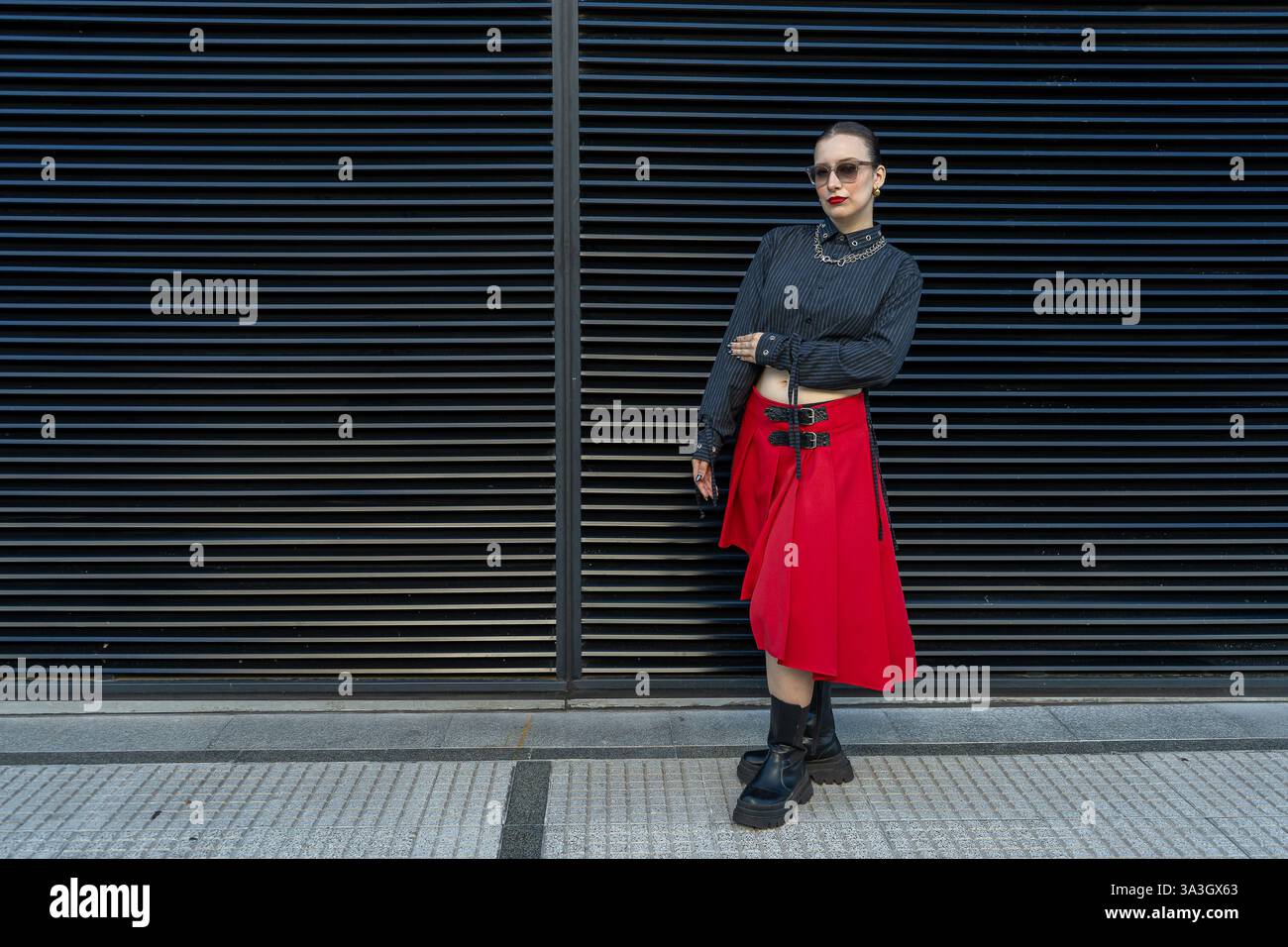 Modello alla moda dallo stile urbano con una gonna rossa e una camicia scura su sfondo nero Foto Stock