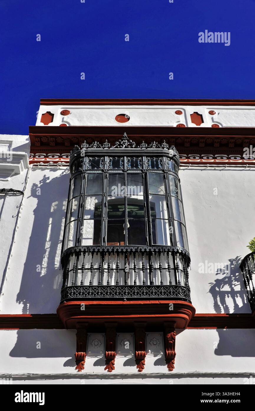Siviglia, Andalusia, Spagna, Europa, una finestra a bovindo elegantemente decorata con vetro e ferro battuto su un edificio bianco e blu, Europa Foto Stock