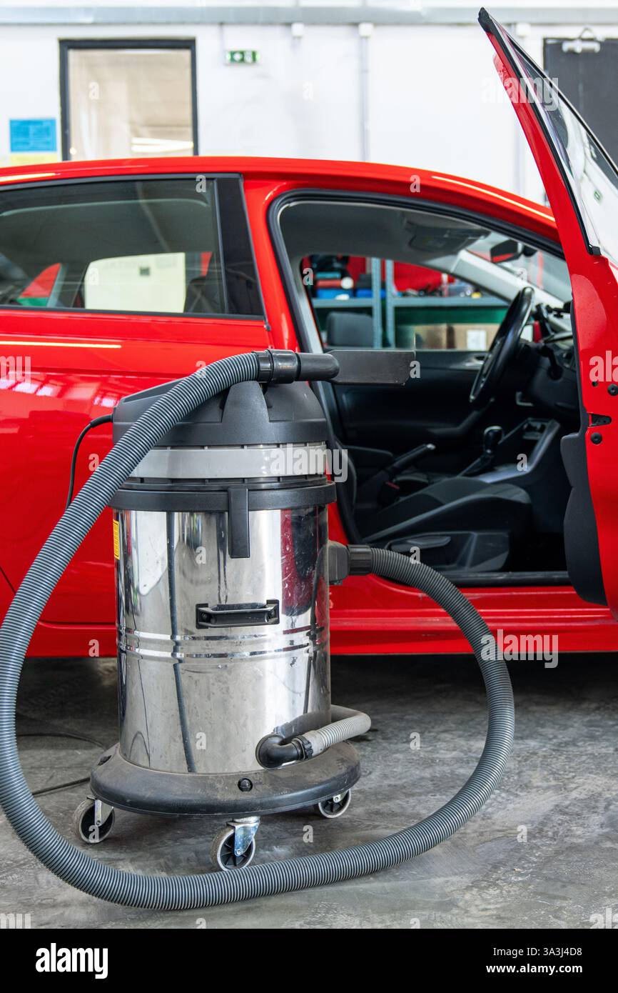 Aspirapolvere accanto all'auto. Lavaggio a secco degli interni. Foto Stock