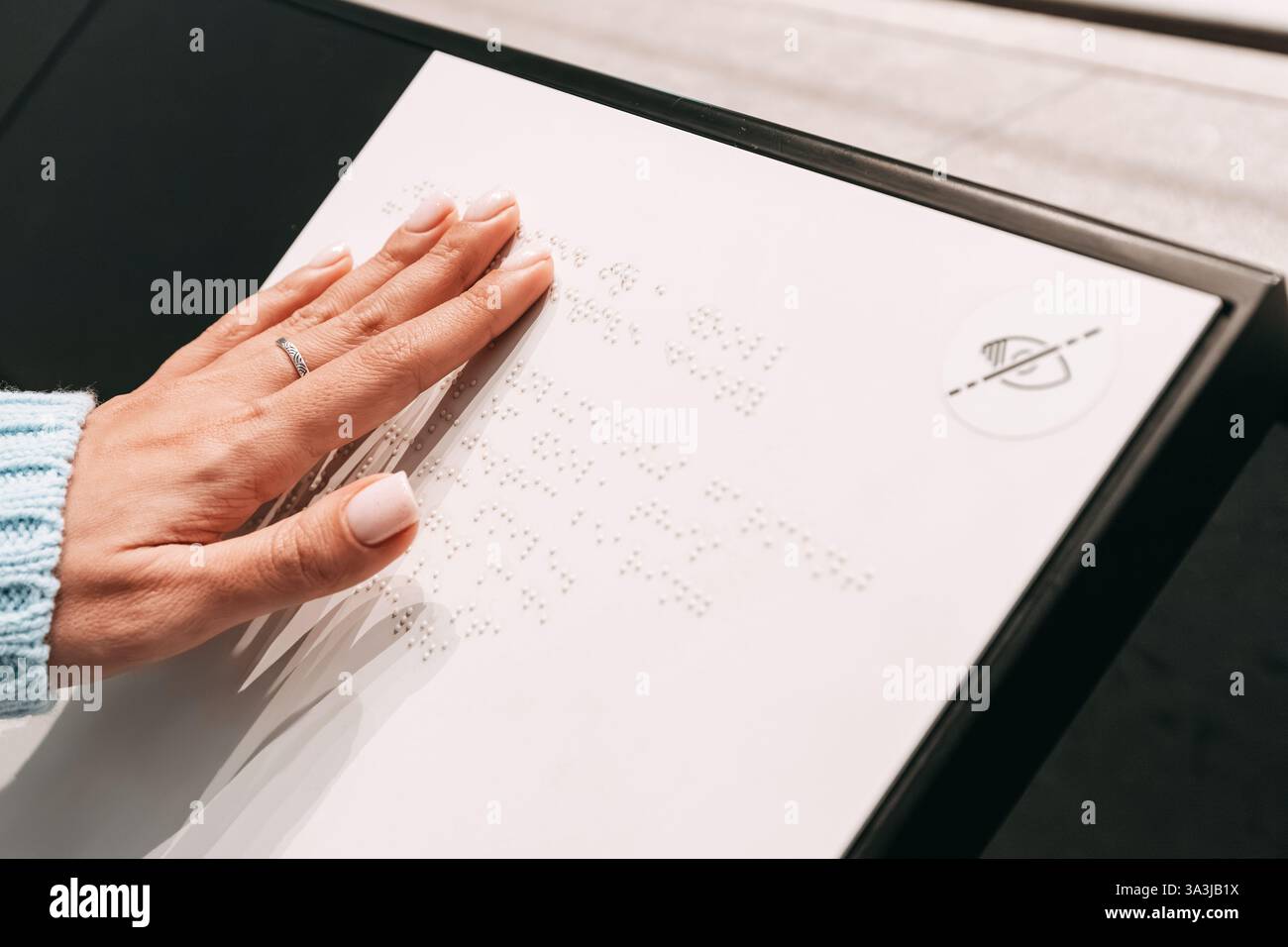 Primo piano di una scritta in braille con lettura a mano femminile su una lavagna nel museo Foto Stock