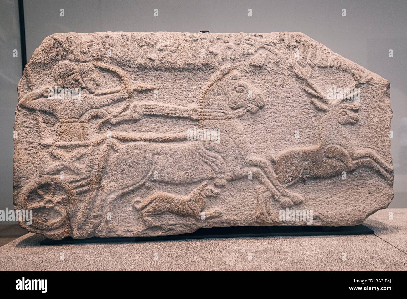 17 gennaio 2025, museo del Louvre di Abu Dhabi, Emirati Arabi Uniti: Antico rilievo in pietra raffigurante la caccia reale con carro da cavallo guerriero Foto Stock