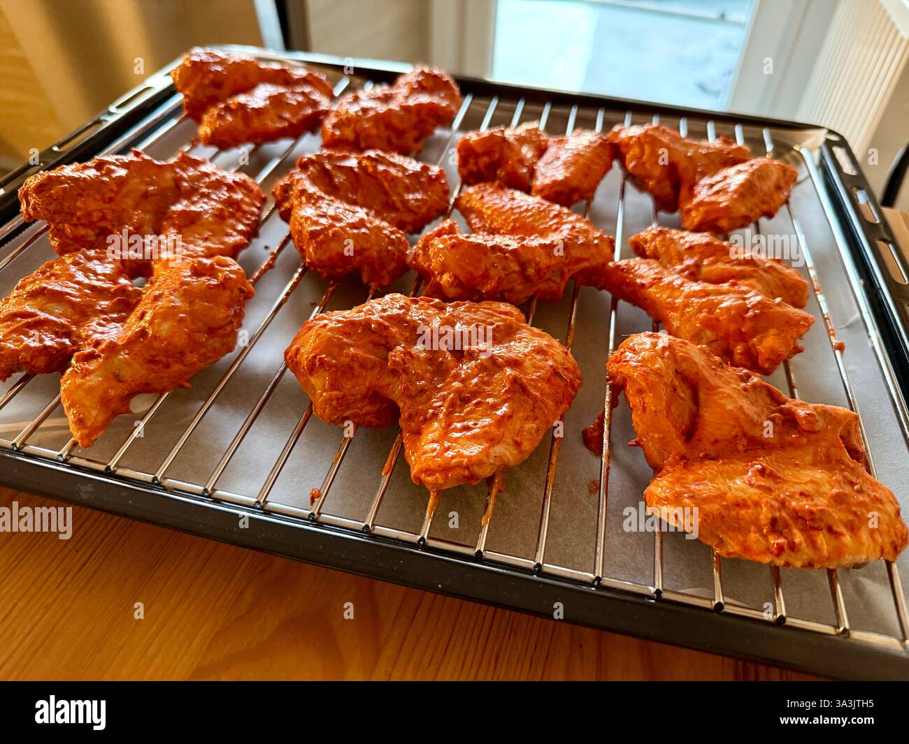 Ali di pollo crude fatte in casa con salsa su griglia metallica Foto Stock