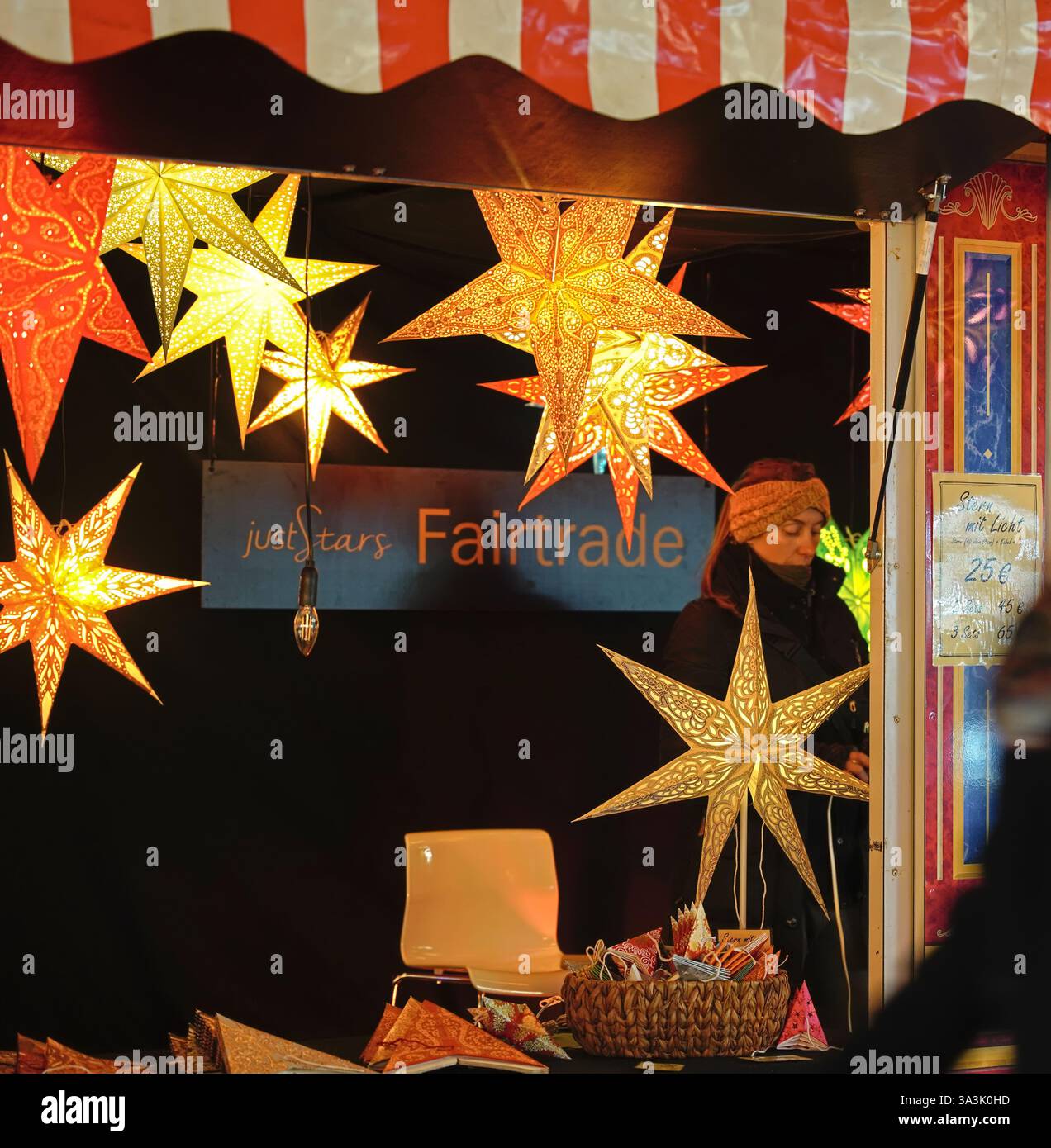 Una donna che vende le stelle dell'Avvento al suo bancone al mercatino di Natale a Potsdamerplatz Berlino Foto Stock