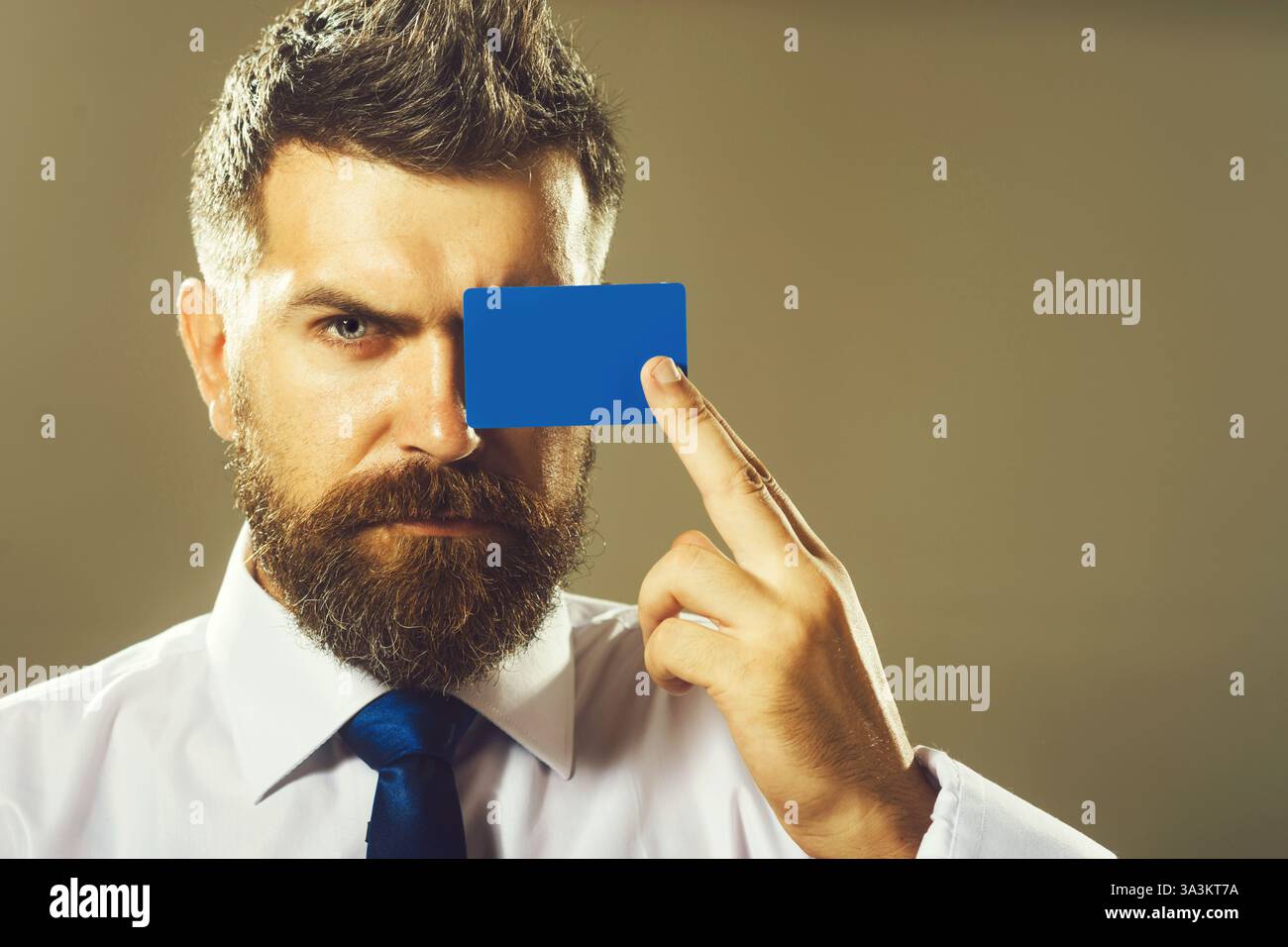 Uomo d'affari in vestibilità formale con carta di credito o di debito. Un uomo serio con la barba che mostra la carta di credito. Bell'uomo con un biglietto da visita in mano. Transazione di pagamento Foto Stock