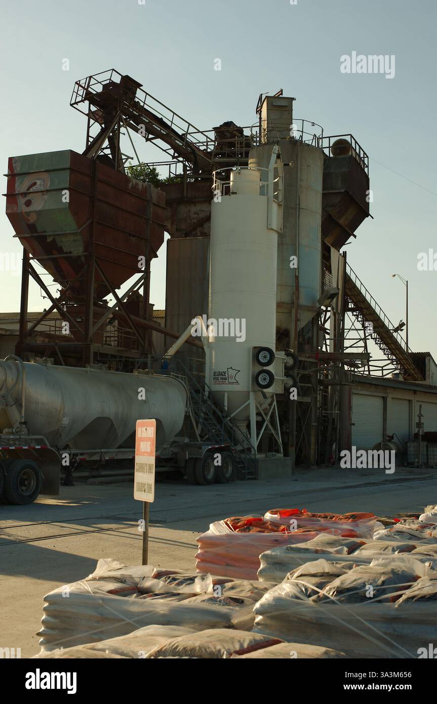 Impianti industriali per calcestruzzo e fornitura di materiali da costruzione. Carrello per cemento grande in primo piano. Oscuramento di un contenitore di stoccaggio alto. Industriale Foto Stock