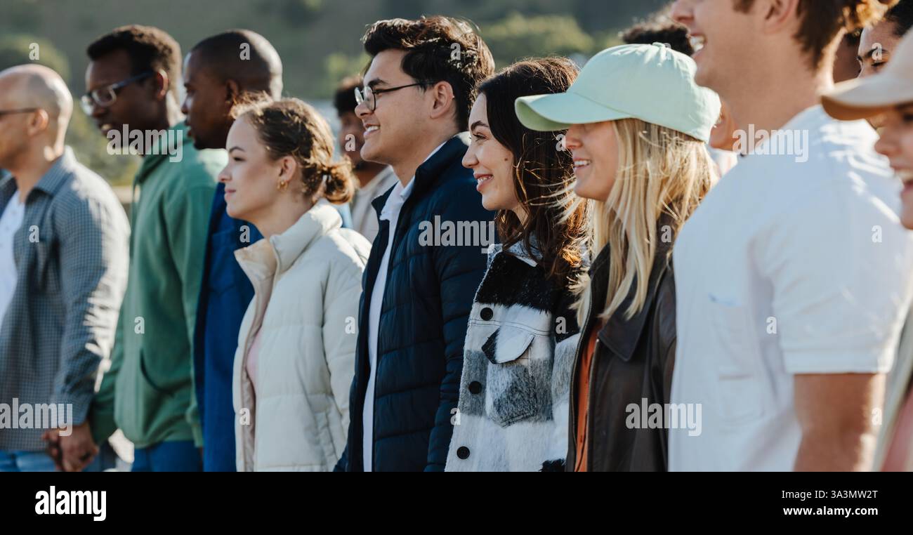 Un gruppo di persone diverse si riunisce all'aperto, esprimendo unità e sostegno per la connessione umana. Gli individui mostrano solidarietà mentre stanno insieme, Foto Stock