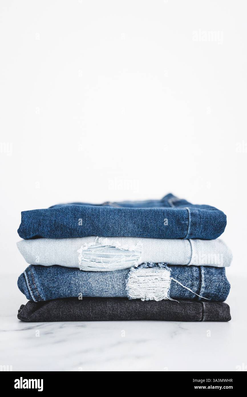 pile di jeans in denim di diversi colori ripiegati e impilati su uno sfondo minimalista Foto Stock pile di jeans in denim di diversi colori ripiegati e impilati su uno sfondo minimalista Foto Stock