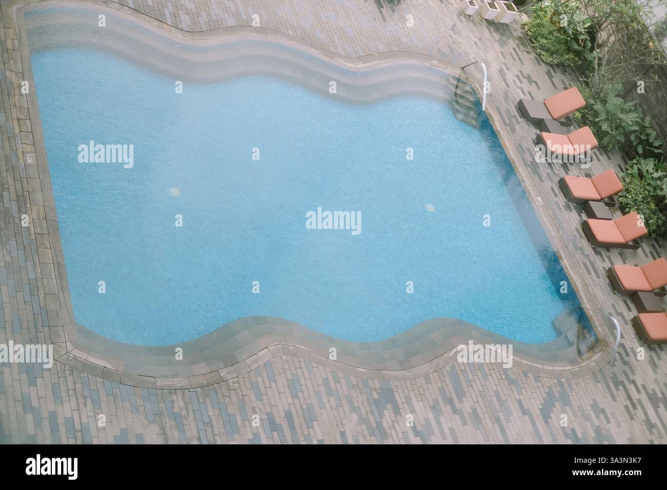 Vista dall'alto della piscina, circondata da sedie a sdraio. Cattura un'atmosfera serena e invitante, perfetta per rappresentare il tempo libero, il relax Foto Stock