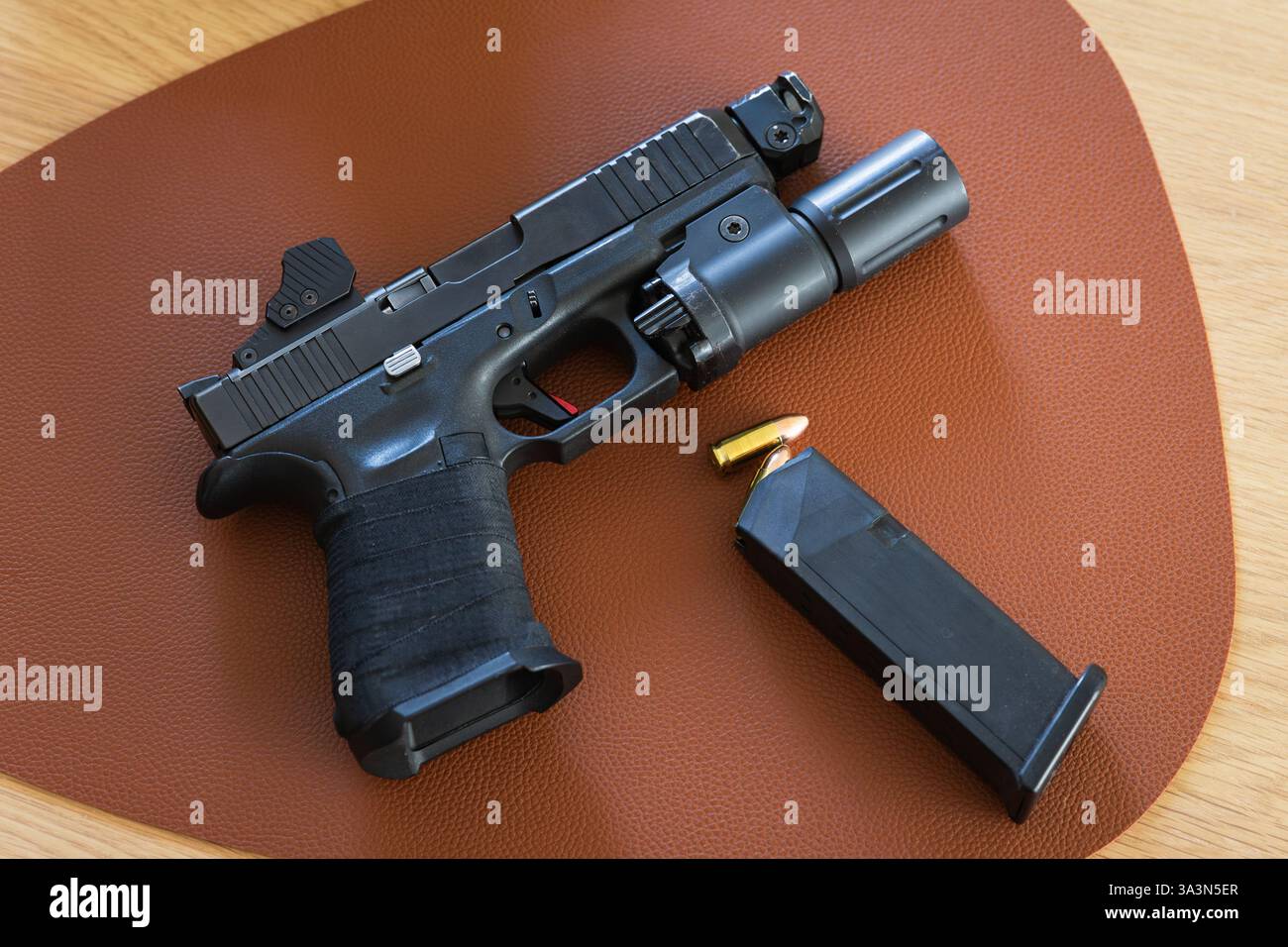 Arma tattica civile, pistola con torcia e punto rosso sul tavolo. Foto Stock