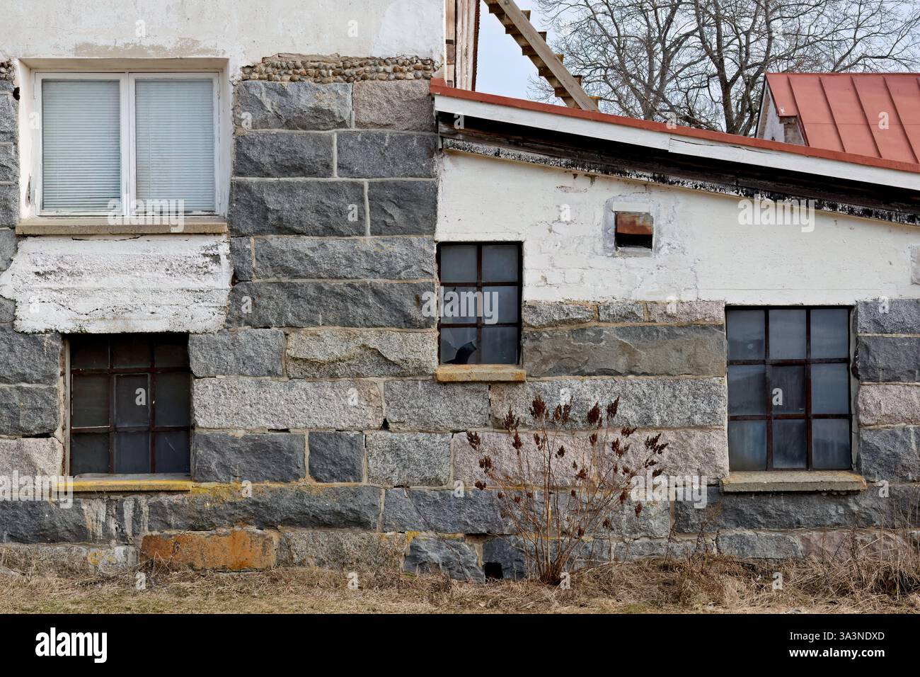 Un vecchio edificio in pietra con finestre di dimensioni diverse sulle pareti Foto Stock