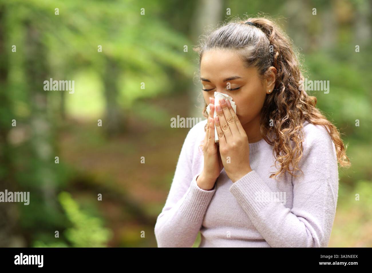 Donna malata che soffia il naso con tessuto che cammina in natura Foto Stock