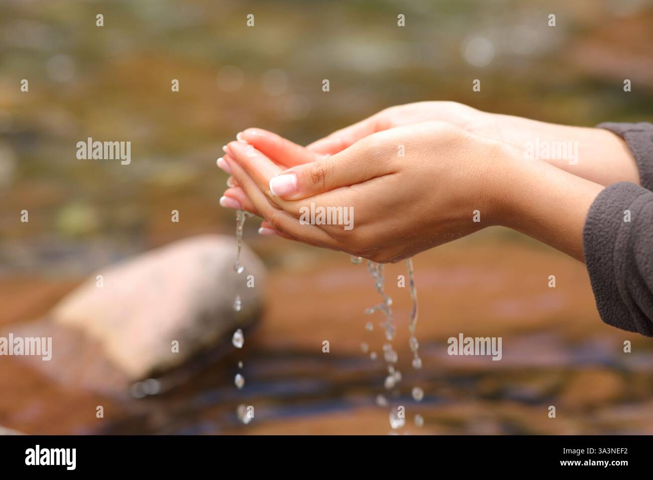 Primo piano ritratto di una donna che cattura l'acqua dal fiume pronta a bere Foto Stock