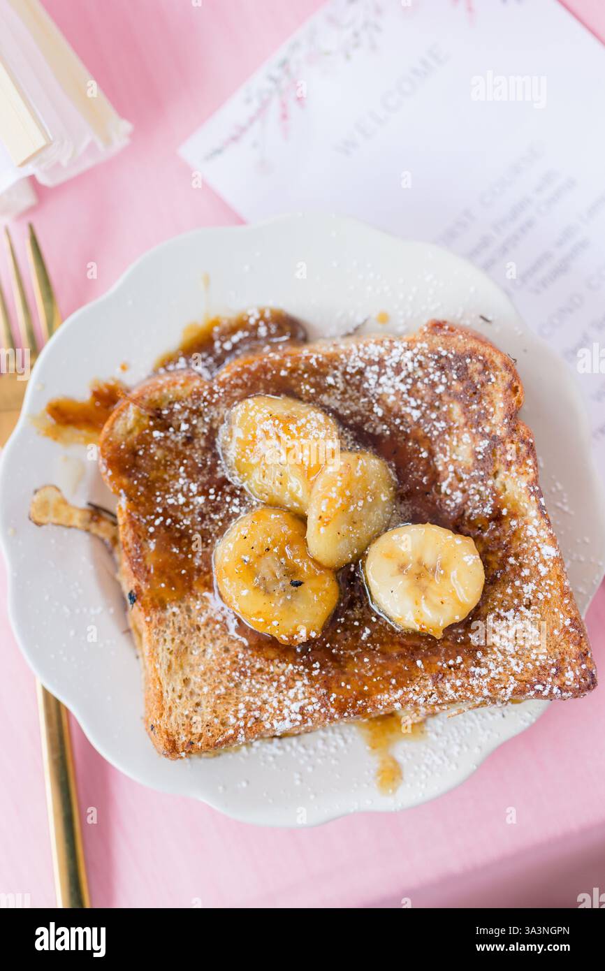 Toast alla francese con banane caramellate e zucchero a velo. Foto Stock
