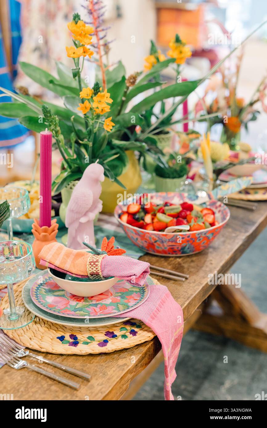 Vivace ambiente da tavolo con decor tropicale e cesto di frutta fresca. Foto Stock