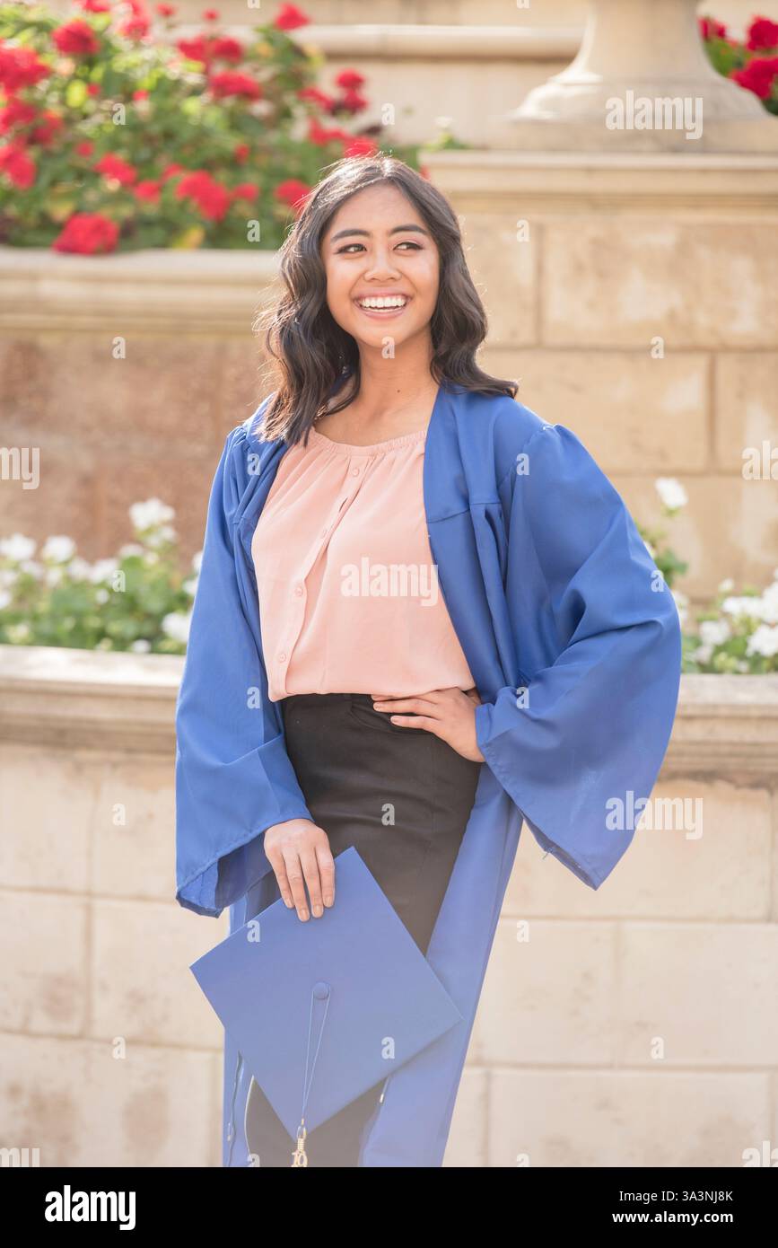 Gioiosa laureata celebra con orgoglio il suo successo con un abito blu Foto Stock