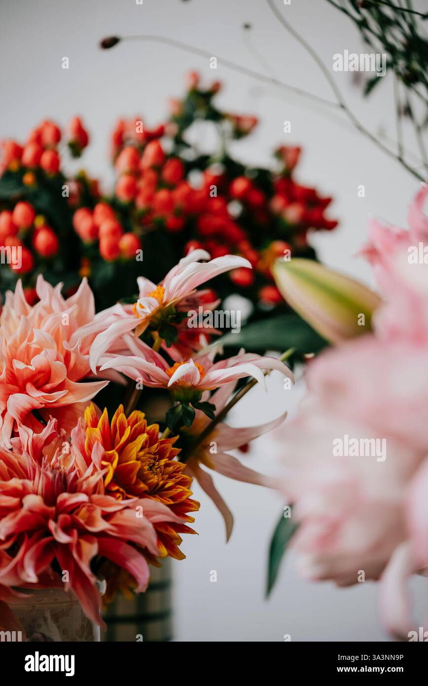 Un bouquet di fiori con fiori rosa e arancio. I fiori sono disposti in un vaso e collocati su un tavolo. La scena è allegra e luminosa, come la Foto Stock