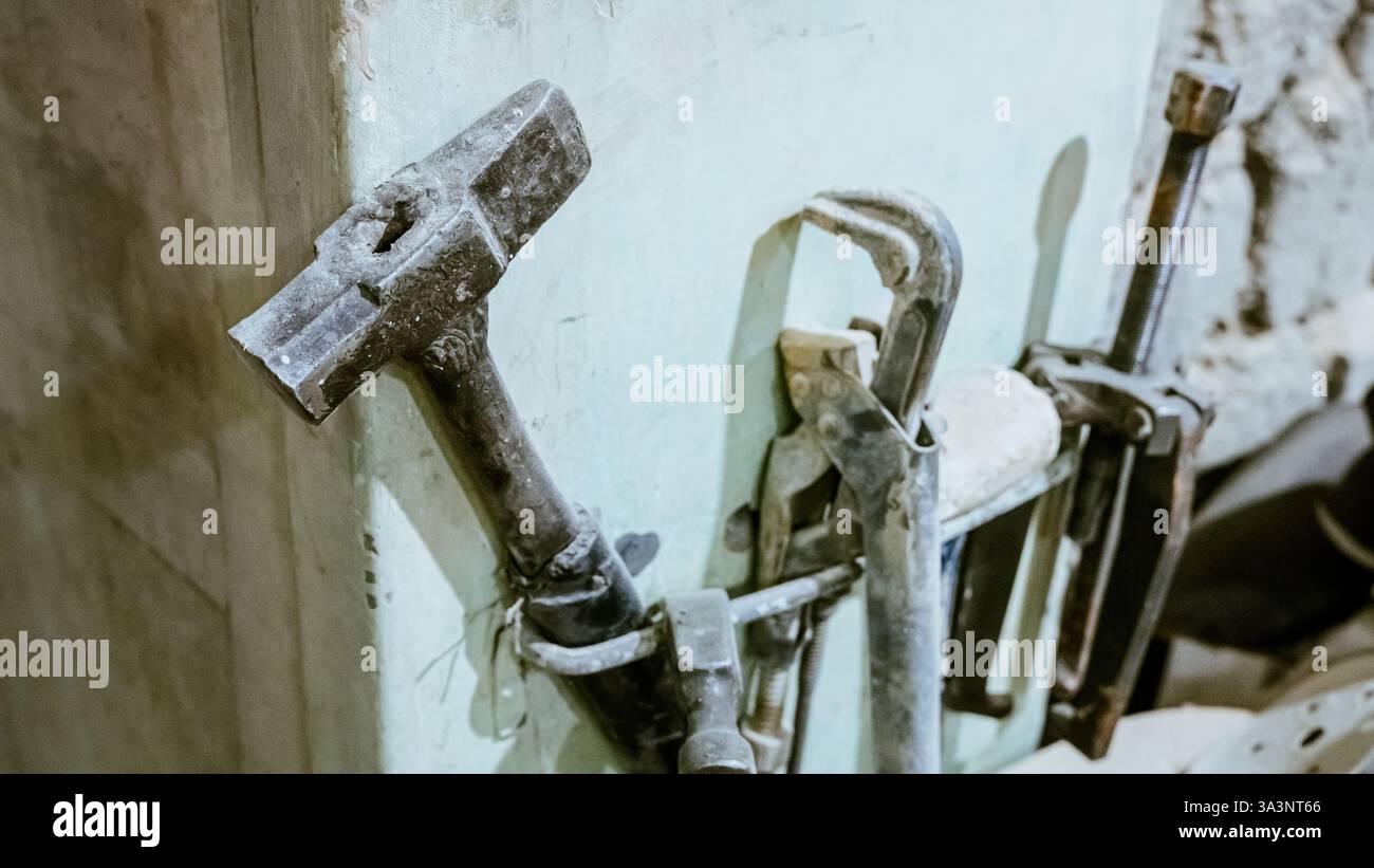 Vari utensili: Lima, cacciavite, martello, pinze, utensili da giardino sono esposti su scaffale in legno all'interno di officine o fabbriche rustiche, officina in una Foto Stock