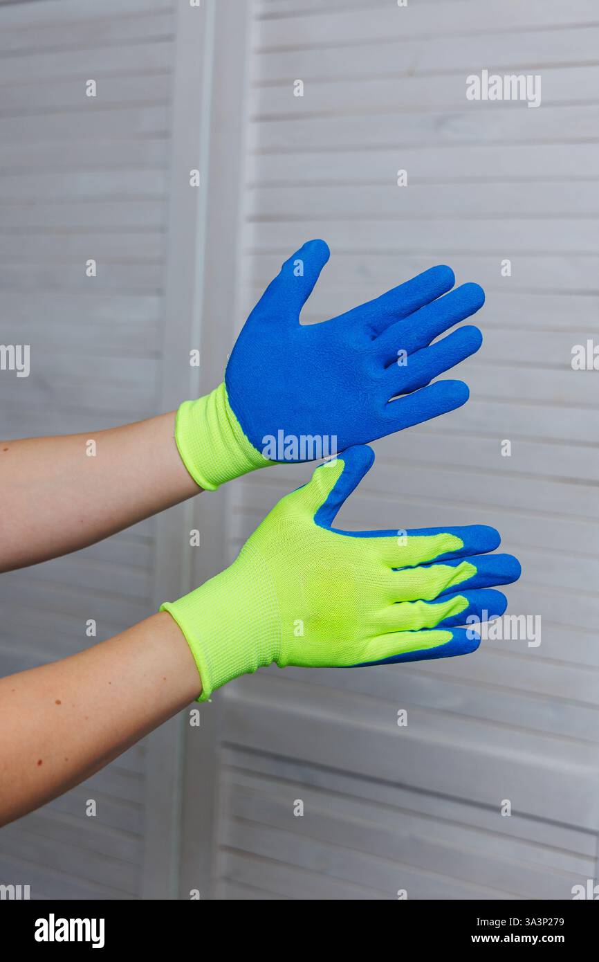 Una persona indossa un vivace paio di guanti giallo e blu al neon, progettati per varie attività, in particolare per le attività di pulizia domestica Foto Stock