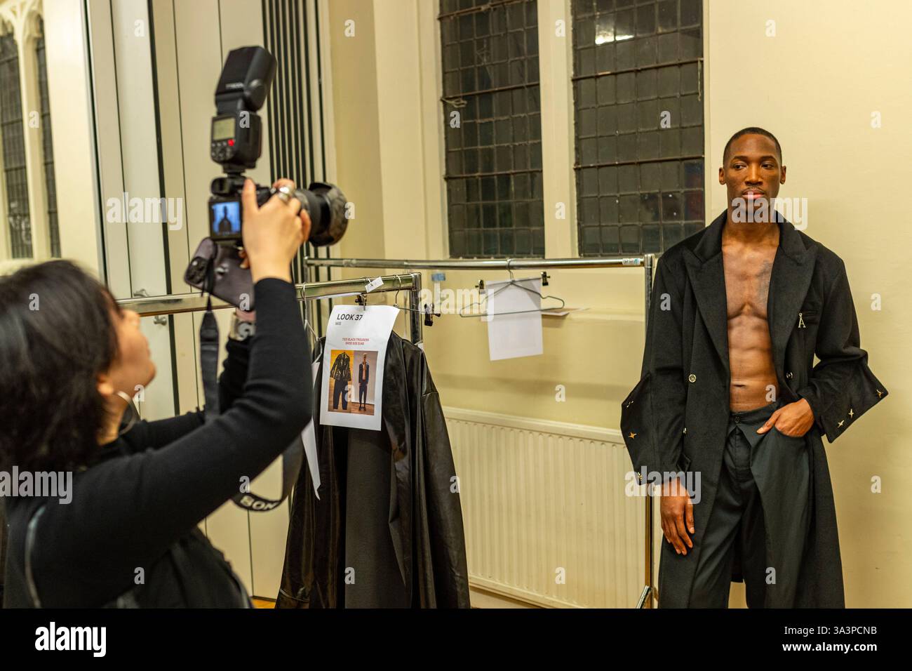 Una modella che posa per una foto nel backstage con un fotografo in una sfilata di moda durante la London Fashion Week 2025 Foto Stock