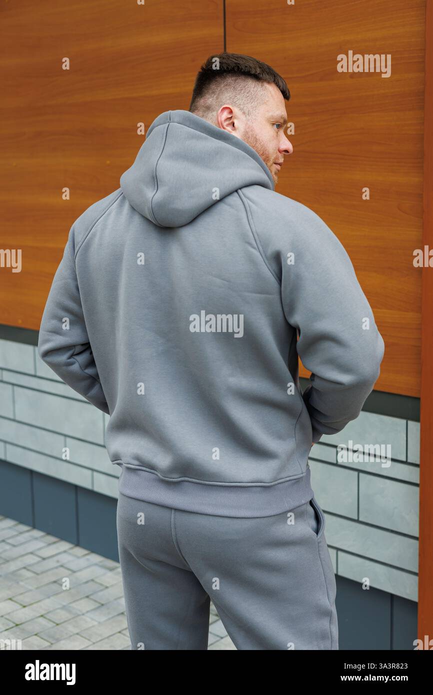 La parte posteriore di un uomo vestito con una comoda felpa con cappuccio grigia, dotata di tasca di canguro sul davanti Foto Stock