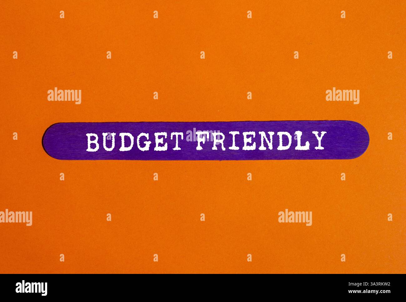 Messaggio economico scritto su un blocco di legno viola su sfondo arancione. Simbolo di budget concettuale. Copia spazio. Foto Stock