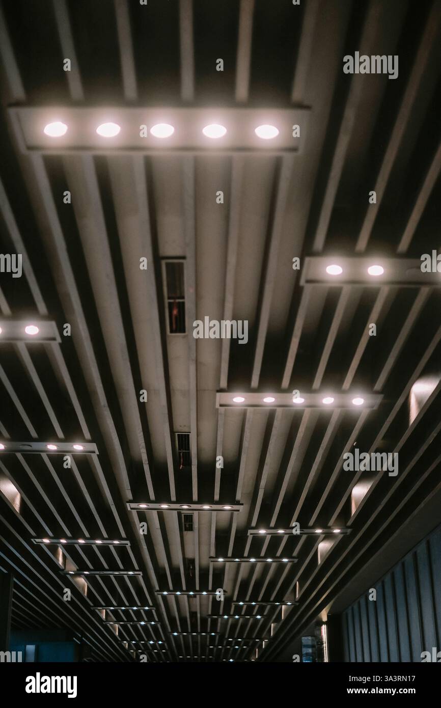Una vista astratta di un soffitto geometrico con struttura in cemento e luci. Design architettonico moderno con un'estetica minimalista. Adatto per la schiena Foto Stock
