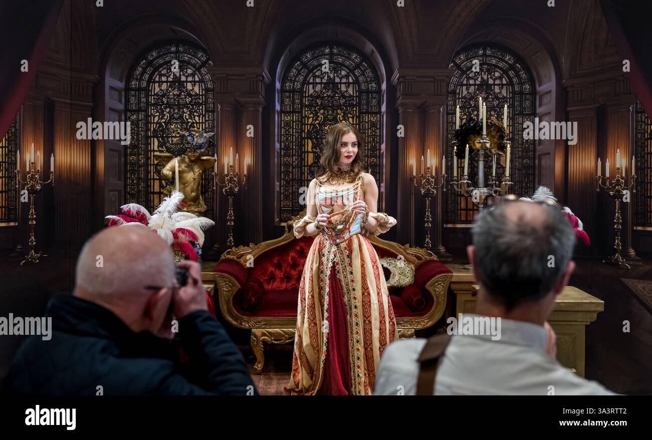 Uomini che fotografano una modella con indosso un costume d'epoca in una scena ornamentale, Regno Unito Foto Stock