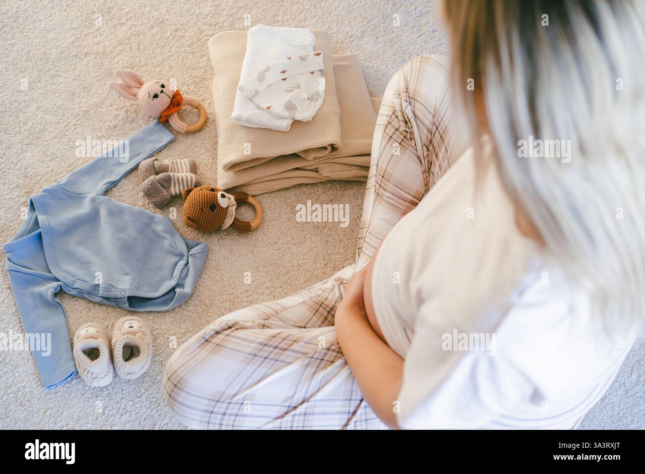 La giovane bella donna in pigiama sta imballando un sacco di cose per il reparto maternità. Il modello con la pancia si sta preparando ad essere madre. Foto Stock