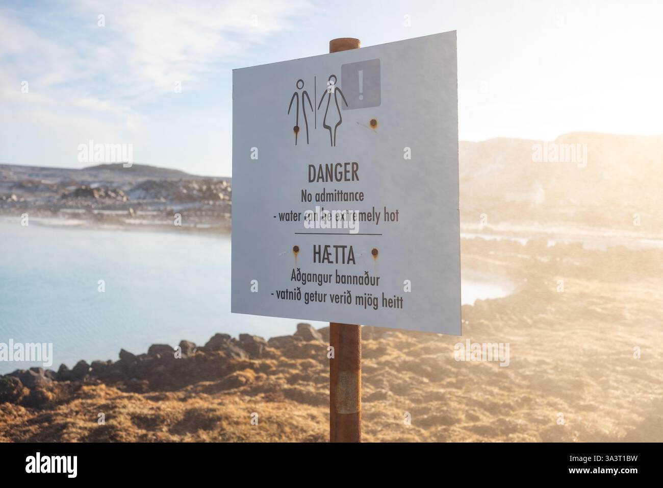 Un cartello segnaletico pericolo acqua molto calda situato tra la centrale elettrica di Svartsengi e la Blue Lagoon Spa vicino a uno dei bacini sottoprodotti dello stabilimento. Foto Stock