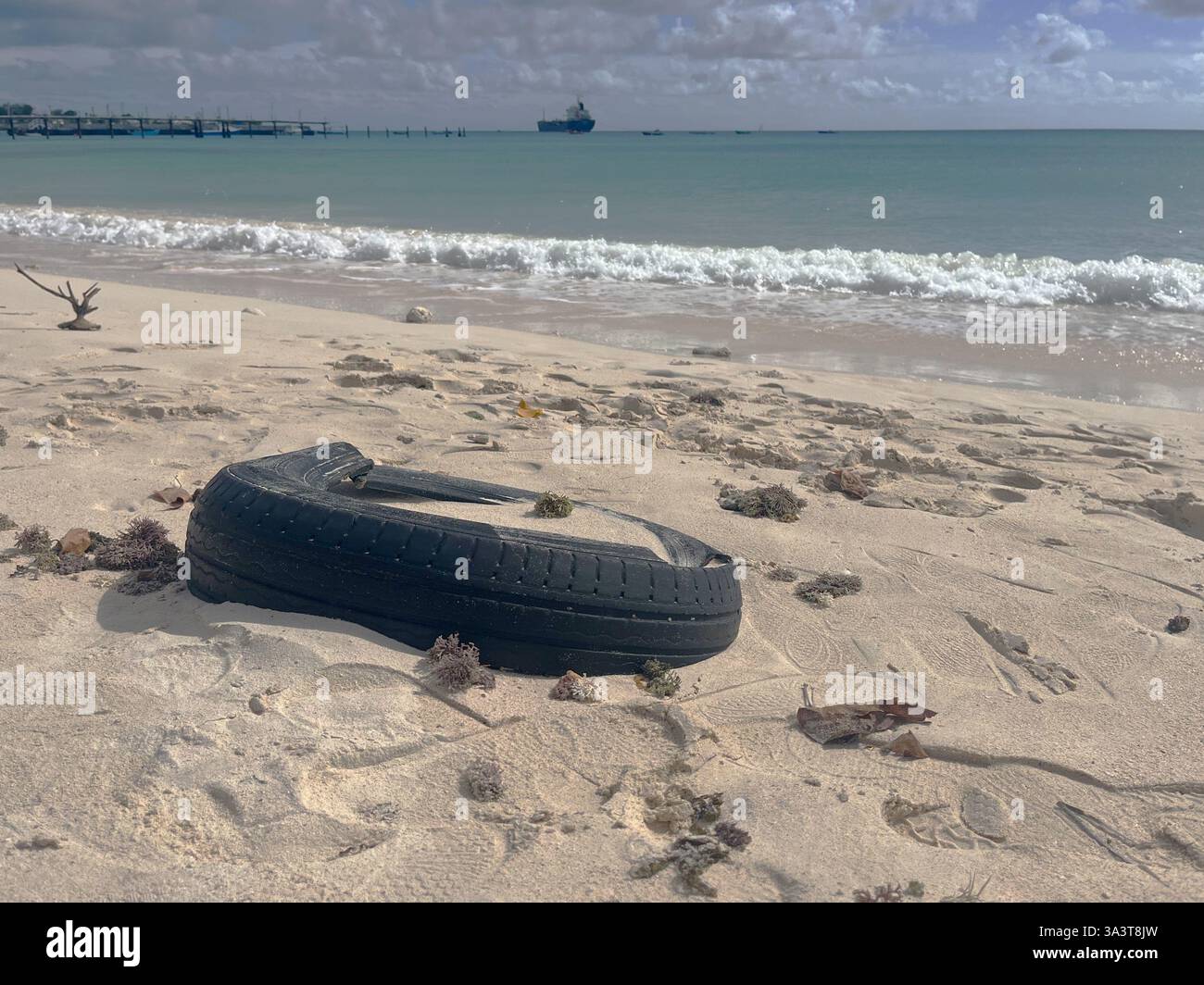 Inquinamento in paradiso - un vecchio pneumatico è stato lavato su una spiaggia tropicale altrimenti bella a Barbados. Foto Stock
