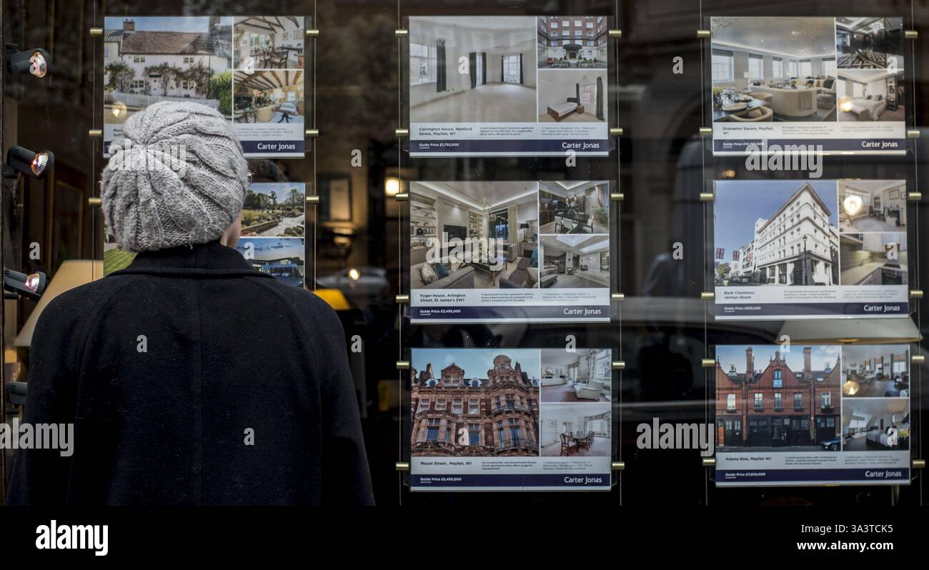 EMBARGO AL 0001 MERCOLEDÌ 13 NOVEMBRE foto del file datata 22/03/17 una donna che guarda case in vendita alla finestra di un agente immobiliare a Mayfair, Londra. Gli acquirenti di case potrebbero in genere risparmiare più di £ 40.000 acquistando una proprietà "superiore del fissatore", secondo le analisi. Il prezzo medio richiesto di una casa di fissaggio è di £ 327.224, che è £ 44.634 in meno rispetto al prezzo tipico di £ 371.858 per una casa in Gran Bretagna, ha detto Rightmove. Data di pubblicazione: Mercoledì 13 novembre 2024. Foto Stock