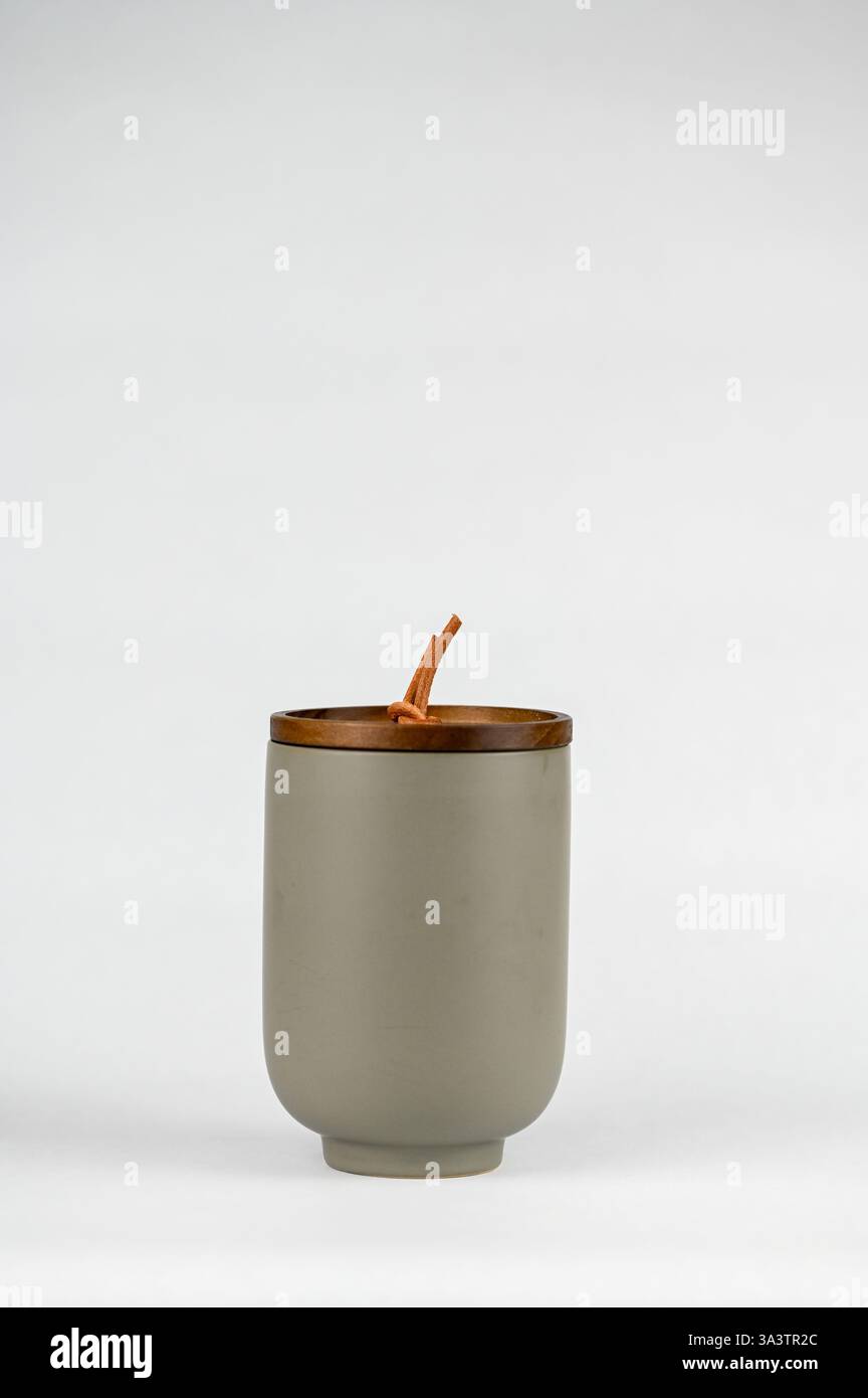 Vaso cilindrico grigio in ceramica con candela profumata e coperchio in legno con rivestimento in pelle Foto Stock